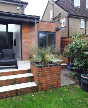 Brick and zinc extension to house in Watford. Brick planters with tropical/jungle planting and rainchain details.